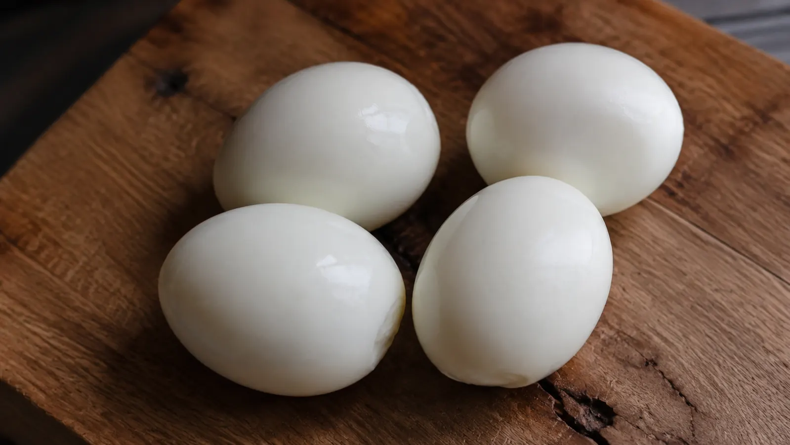 Perfectly peeled hard-boiled eggs with smooth white surfaces on a wooden cutting board