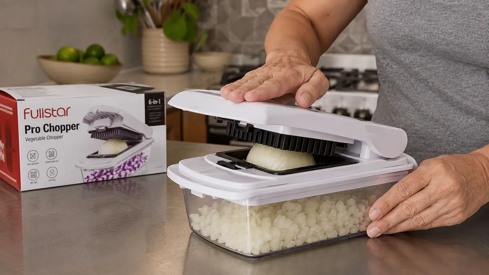Hand pressing down on the Fullstar Pro Chopper blade grid over a halved onion in the container